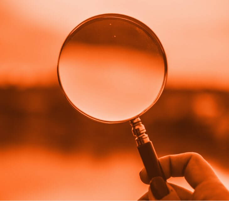 A hand holding a magnifying glass