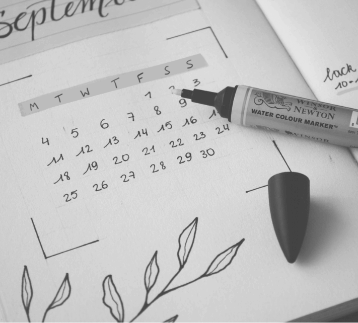 Pen resting on paper with a calendar printed on it.